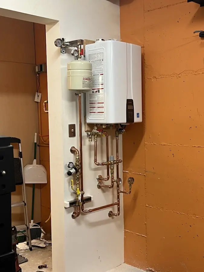 Plumbing technician inspecting water heater connections in North Elba